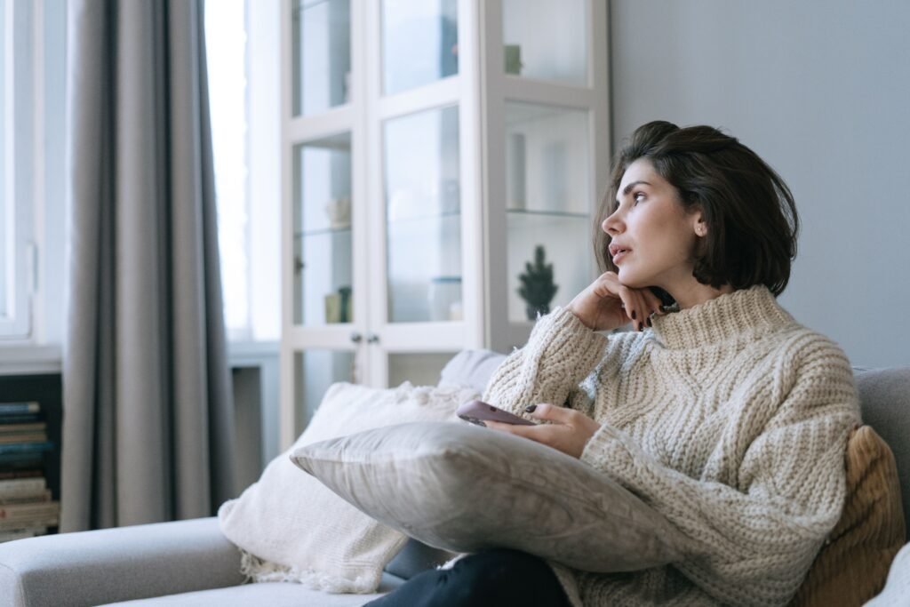 Woman reflecting on an uncertain romantic connection while looking at her phone.