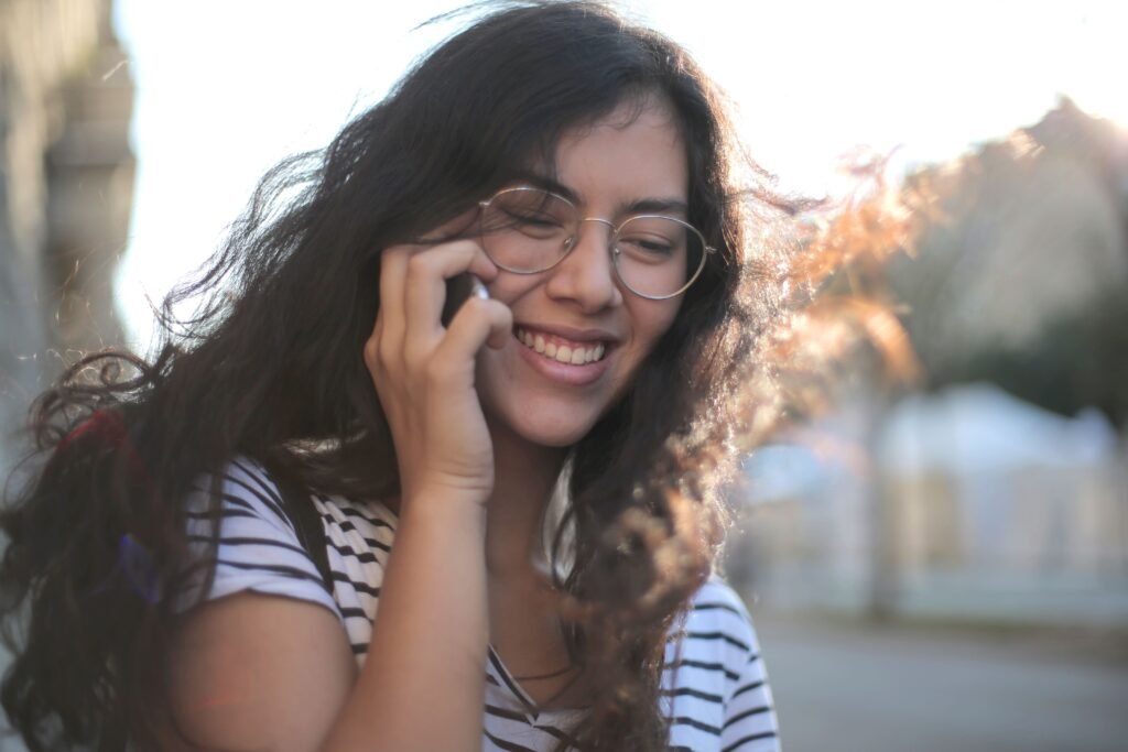 Woman smiling during a phone conversation, representing emotional connection through voice.