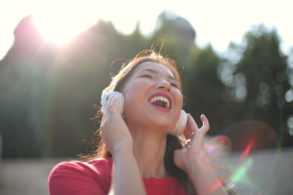 Woman smiling while listening through headphones, representing attraction through voice and personality.